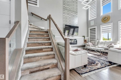 Staircase featuring wood-finish treads with carpet runners and glass railings - 715 Ebbers Place Nw, Edmonton, AB 