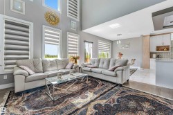 Double-height living area featuring high ceilings, multiple window placements, and wood-finish flooring - 