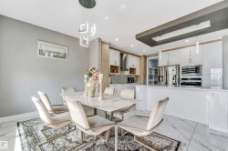 Open-concept dining area and kitchen featuring marble-finish flooring and a contemporary chandelier - 