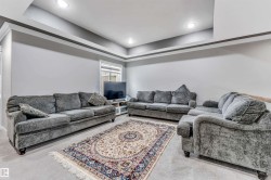 Spacious living area featuring a tray ceiling with recessed lighting, light gray wall paint, and carpet flooring - 