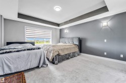Carpeted room featuring a large window with horizontal blinds, tray ceiling, and wall-mounted sconces - 