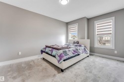 Bedroom featuring two windows with horizontal blinds, light grey carpeting, and light grey walls - 