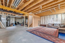 Expansive unfinished basement featuring exposed wood joists and concrete flooring - 