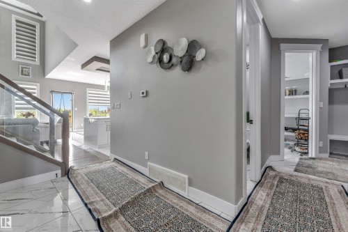 Foyer entry featuring marble-look tile flooring and a glass-paneled staircase - 715 Ebbers Place Nw, Edmonton, AB 