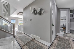 Foyer entry featuring marble-look tile flooring and a glass-paneled staircase - 