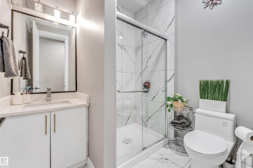 Bathroom featuring a white vanity with a light-toned countertop, a framed rectangular mirror, and a shower with a sliding glass door - 715 Ebbers Place Nw, Edmonton, AB 