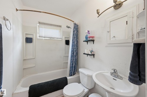 White bathroom featuring a pedestal sink, toilet, and a combined tub/shower unit - 11325 101 Street, Edmonton, AB 