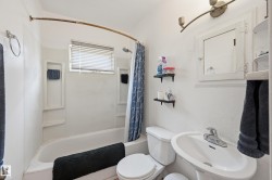 White bathroom featuring a pedestal sink, toilet, and a combined tub/shower unit - 