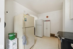 Kitchen area featuring white walls, light-colored flooring, and visible appliances - 