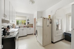 Kitchen featuring white cabinetry, a built-in electric range, a window above the sink, a tiled backsplash, and a recessed wall cabinet with glass doors - 