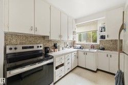 Kitchen featuring white cabinetry, tile backsplash, built-in sink, and a window - 