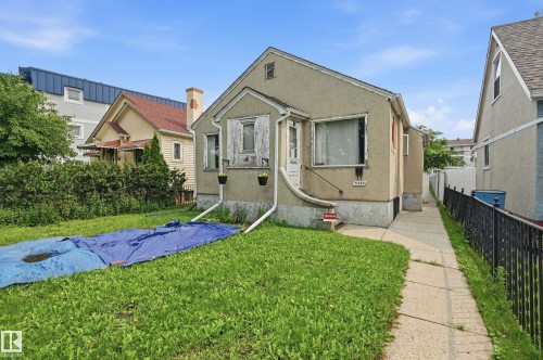 Stucco exterior with a peaked roofline, front-facing window, and concrete entry path - 11325 101 Street, Edmonton, AB 