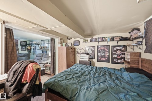 Bedroom featuring a wood-finish bed frame, light-toned walls, and open shelving - 11325 101 Street, Edmonton, AB 