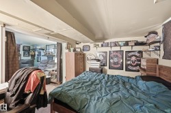 Bedroom featuring a wood-finish bed frame, light-toned walls, and open shelving - 