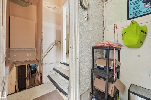 Stairwell featuring a metal handrail, painted risers, and textured wall finishes - 11325 101 Street, Edmonton, AB 