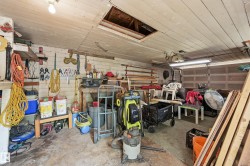 Utility space featuring a wood-plank ceiling, concrete flooring, and a roll-up garage door - 