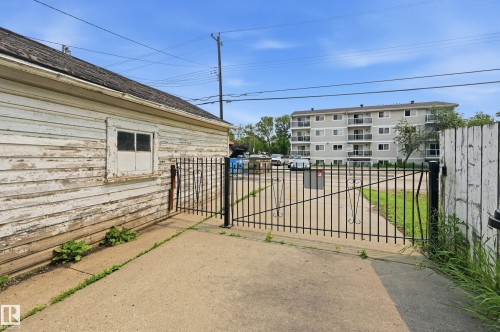 Concrete driveway with a black metal gate and wood fence - 11325 101 Street, Edmonton, AB 
