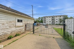 Concrete driveway with a black metal gate and wood fence - 