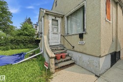 Stucco exterior featuring an entry door with a storm door, a metal handrail, and concrete steps - 
