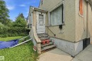 Stucco exterior featuring an entry door with a storm door, a metal handrail, and concrete steps - 11325 101 Street, Edmonton, AB 