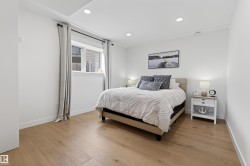 Bright bedroom featuring light wood-finish flooring, white baseboards, and a window with white trim - 