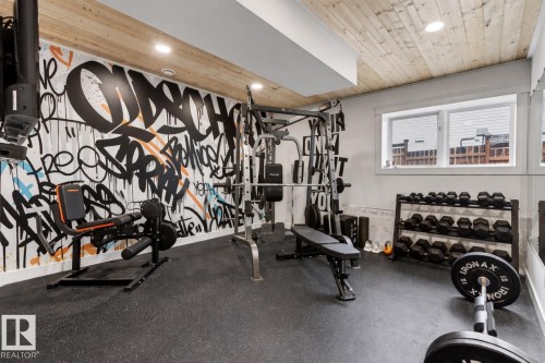 Dedicated fitness space featuring a graffiti-style accent wall, wood-finish ceiling, recessed lighting, and resilient rubber flooring - 711 Beach Avenue, Cold Lake, AB - Indoor Photo Showing Gym Room