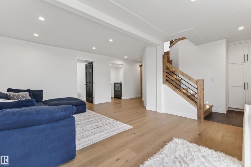 Modern staircase with light wood newel posts, handrail, and black metal balusters - 711 Beach Avenue, Cold Lake, AB - Indoor Photo Showing Living Room