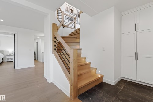 Modern staircase featuring wood treads with integrated lighting, a natural wood newel post, and minimalist black metal balusters - 711 Beach Avenue, Cold Lake, AB - Indoor Photo Showing Other Room