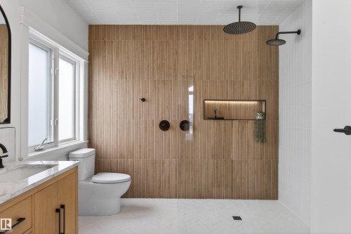 Walk-in shower with wood-finish fluted wall tile, dual matte black shower heads, and an illuminated recessed niche - 711 Beach Avenue, Cold Lake, AB - Indoor Photo Showing Bathroom