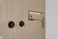 Textured paneling with integrated shower niche featuring recessed lighting and matte black fixtures - 