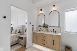 Double vanity with wood-finish cabinetry, quartz countertop, and dual arched mirrors with matte black sconce lighting - 