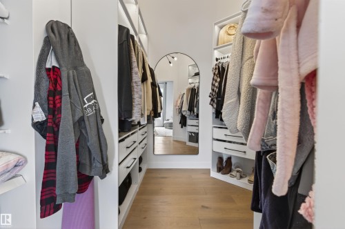 Custom closet system featuring wood-finish flooring, white cabinetry, integrated shelving, and multiple hanging rods - 711 Beach Avenue, Cold Lake, AB - Indoor With Storage