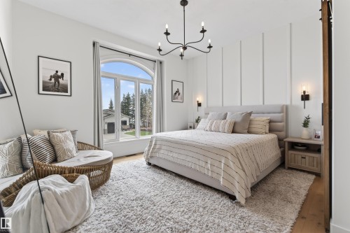 Spacious room featuring a large arched window, a textured accent wall, a multi-light chandelier, and recessed lighting - 711 Beach Avenue, Cold Lake, AB - Indoor Photo Showing Bedroom
