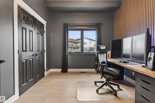 Room featuring light wood-finish flooring, dark gray walls, and a window with dark drapery - 711 Beach Avenue, Cold Lake, AB - Indoor Photo Showing Office