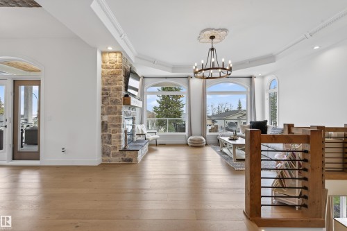 Spacious room featuring light wood-finish flooring, a stone-clad fireplace with a hearth and wood mantel, and multiple arched windows - 711 Beach Avenue, Cold Lake, AB - Indoor