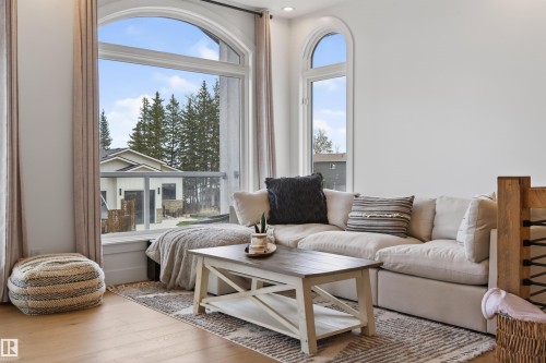 Arched picture window with glass railing balcony, wood-finish flooring, and white painted walls - 711 Beach Avenue, Cold Lake, AB - Indoor Photo Showing Living Room