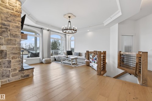Spacious living area featuring light wood-finish flooring, a stone-clad fireplace, and arched windows - 711 Beach Avenue, Cold Lake, AB - Indoor Photo Showing Living Room