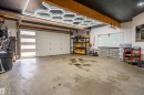 Garage featuring a modern white overhead door with horizontal frosted glass inserts, exposed wood ceiling beams, and contemporary hexagonal ceiling lighting - 711 Beach Avenue, Cold Lake, AB  - Indoor Photo Showing Garage 
