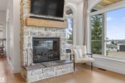 Stone-clad fireplace featuring a rustic wood mantel and a glass-front firebox - 