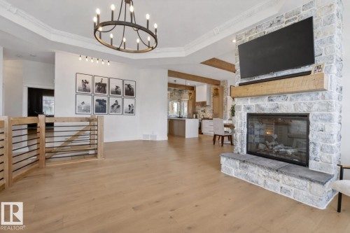 Stone-clad fireplace with wood mantel and hearth, featuring a glass-front firebox - 711 Beach Avenue, Cold Lake, AB - Indoor Photo Showing Living Room With Fireplace