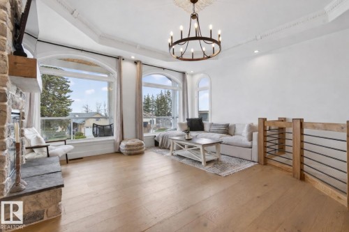 Spacious interior with natural wood-finish flooring, a stone-clad fireplace with wood mantel, and large arched windows providing abundant natural light - 711 Beach Avenue, Cold Lake, AB - Indoor Photo Showing Living Room