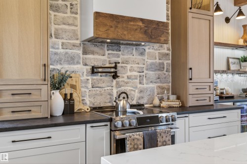 Kitchen featuring stone backsplash, wood-finish cabinetry, black countertops, and stainless steel range - 711 Beach Avenue, Cold Lake, AB - Indoor Photo Showing Kitchen With Upgraded Kitchen