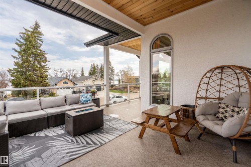 Covered outdoor patio with a textured ceiling, stucco exterior, and glass railing - 711 Beach Avenue, Cold Lake, AB - Outdoor With Deck Patio Veranda With Exterior