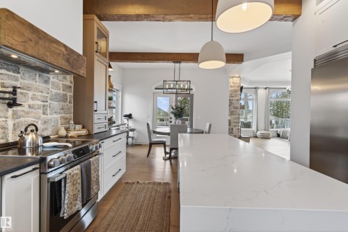 Gourmet kitchen featuring a white stone island, stainless steel appliances, and a stone-clad range hood - 711 Beach Avenue, Cold Lake, AB - Indoor Photo Showing Kitchen With Upgraded Kitchen