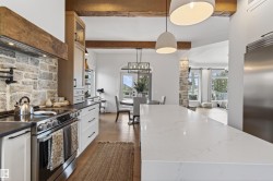 Gourmet kitchen featuring a white stone island, stainless steel appliances, and a stone-clad range hood - 