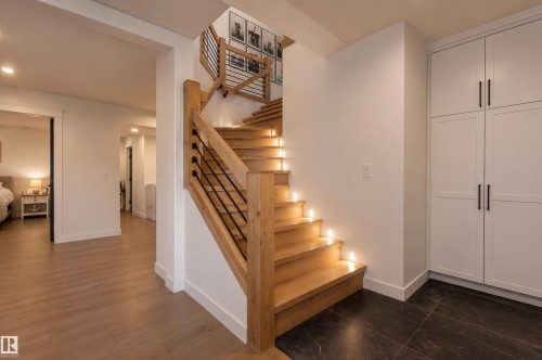Wood staircase with integrated tread lighting, black metal balusters, and natural wood newel posts - 711 Beach Avenue, Cold Lake, AB - Indoor Photo Showing Other Room