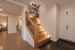 Wood staircase with integrated tread lighting, black metal balusters, and natural wood newel posts - 