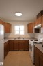 U-shaped kitchen featuring wood cabinetry, a double basin stainless steel sink, and light-toned countertops - 11120 132 Street, Edmonton, AB 