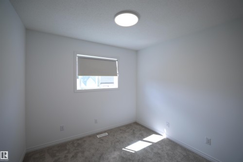 Neutral white walls with a single window featuring a roller shade - 11120 132 Street, Edmonton, AB 