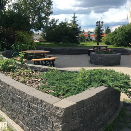 Landscaped outdoor area featuring a paver retaining wall and a central paver fire pit - 46 13435 97 Street, Edmonton, AB 